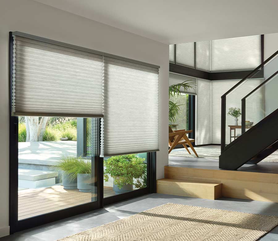 Pale grey cellular shades drawn part way over a wide sliding door onto a garden terrace