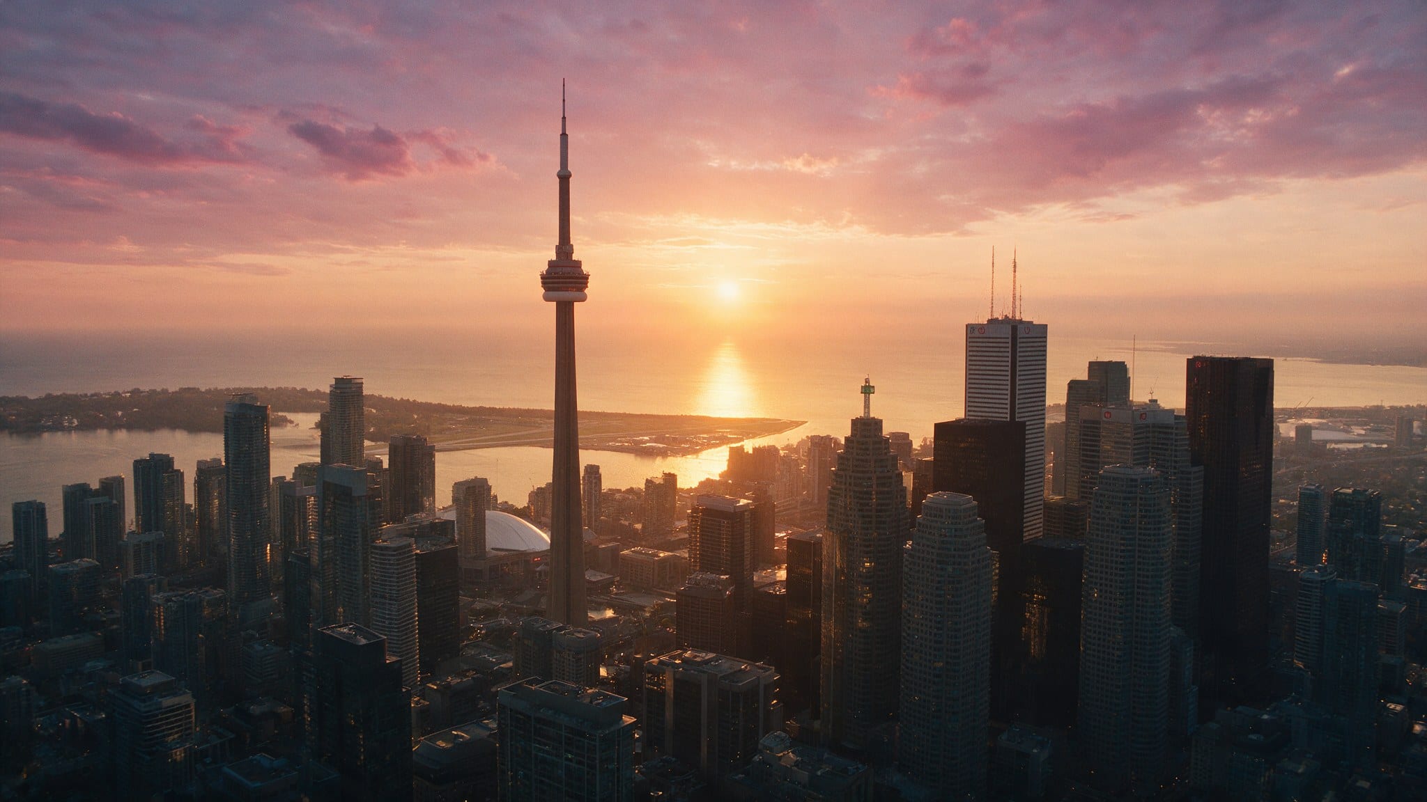 The Toronto skyline at golden hour, seen across a wall of condo glass