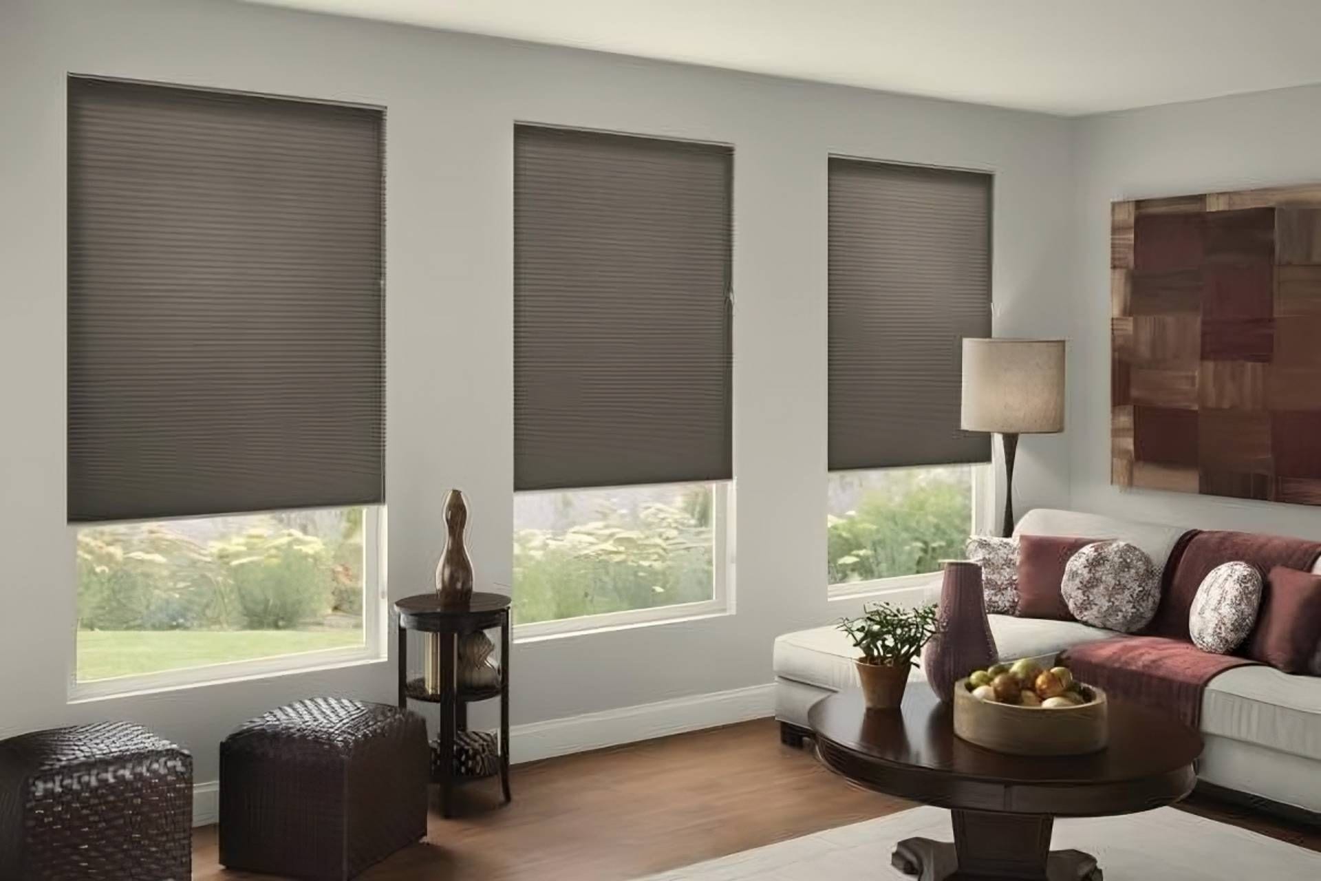 Brown cellular shades lowered part way on three windows of a living room with a white sectional