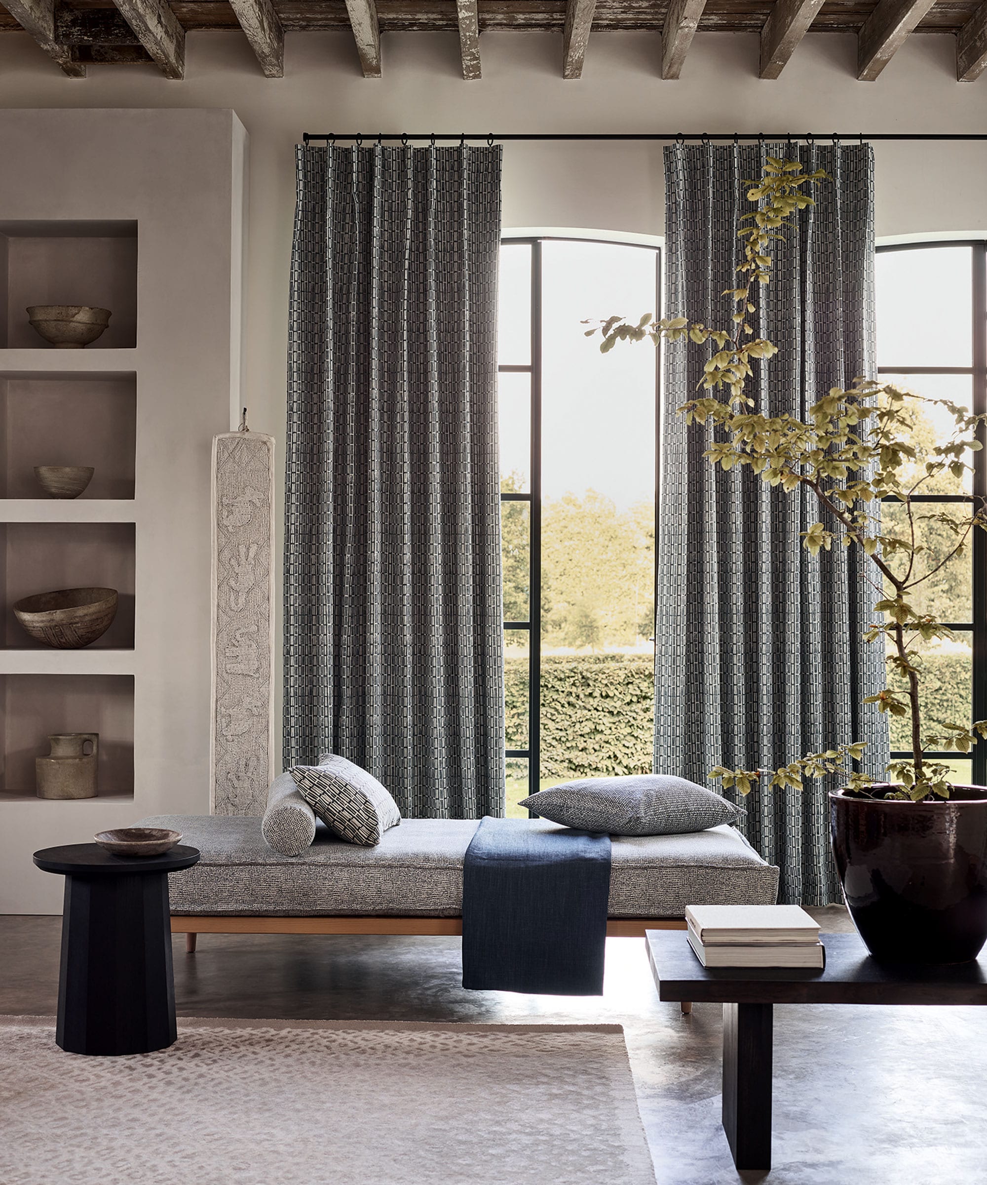 Patterned woven curtains on rings across arched doors beside a daybed