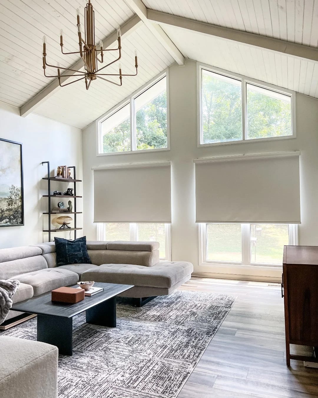 Ivory roller shades lowered on two tall windows under a vaulted white ceiling in a living room
