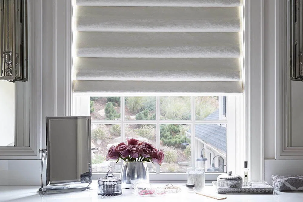 A white roman shade with soft folds over a dressing room window