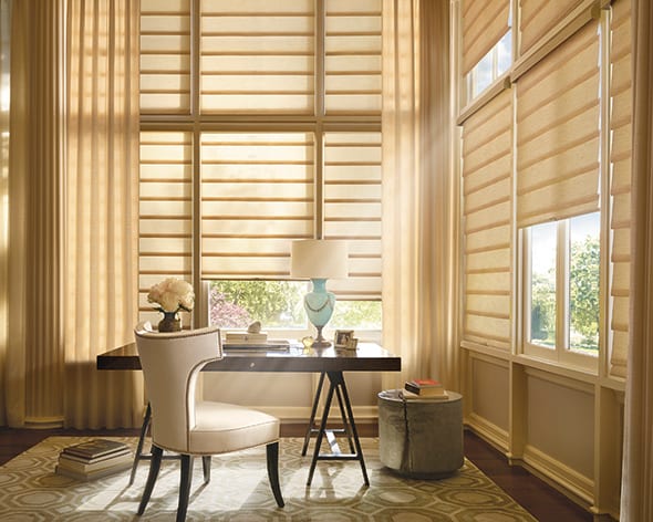 Sheer gold roman shades on tall windows in a home office with a writing desk