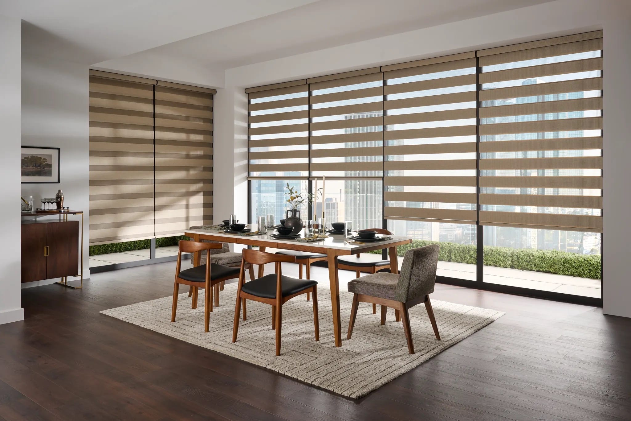 Taupe zebra shades along a glass wall in a dining room, the bands open to a city terrace